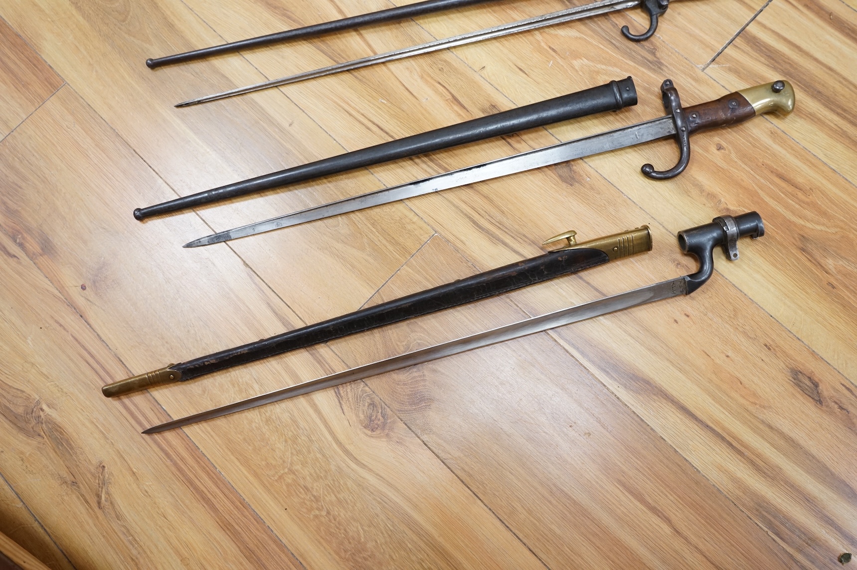 Three bayonets; a gras bayonet, a Lebel bayonet and an Indian Enfield style triangular socket bayonet, all in the original scabbards